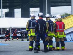 倒壊建物に消防団が放水している写真