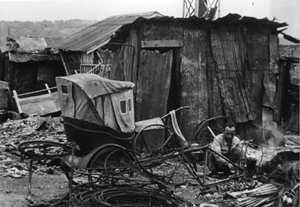 バラックの前で「リンタク」を修理する