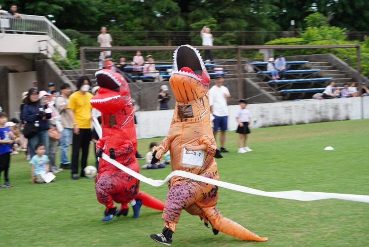 恐竜の着ぐるみを来た人が走っている写真