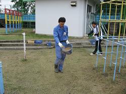 冬芝種まきをする職員の写真