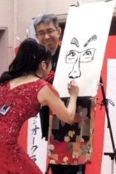 似顔絵を描いてもらっている区長
