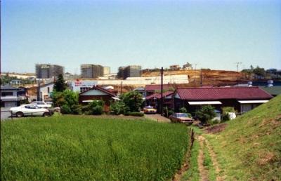 バス停「上白根入口」付近から見た建設中の県営上白根ハイツ。手前は草地。中央には平屋で赤い屋根の住宅。
