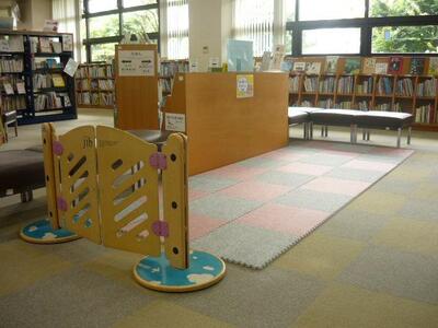 靴脱ぎスペースの画像です。フロアタイルがソファと書架で囲まれています。