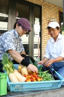 加藤さんと佐々木さんが採れたて野菜を囲んだ写真