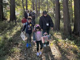 숲에서 재료가 되는 나뭇가지 등을 찾는 아이들과 대학생