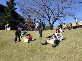 Los niños y el estudiante universitario que realizan césped resbalando usando el cartón arrugado