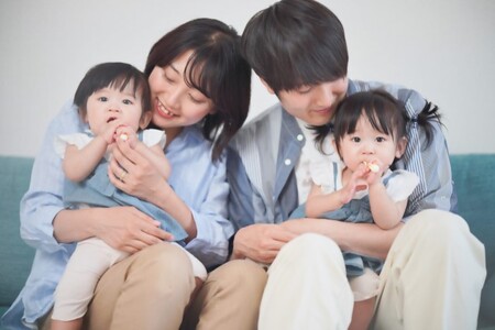 お子さんの歯みがきを膝にのせて見守る両親