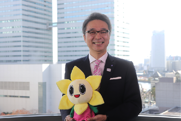 Thị trưởng Teraoka tươi cười cầm một món đồ chơi nhồi bông có hình nhân vật linh vật của Nishi Ward, Shimaro-chan.
