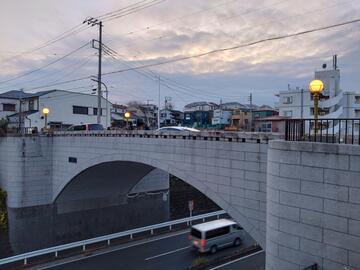 夕暮れの空の下、柔らかな灯りがともった霞橋の全景 