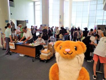 来場客でにぎわう食中毒予防キャンペーン会場と、カメラ目線のタッチーくん