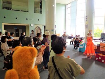 手洗いのやり方を実演するピエロとそれをまねする参加者。タッチーくんもその様子を眺めている。